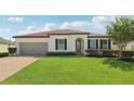 Charming one-story home with a well-manicured lawn, brick driveway, and elegant architectural details at 11313 Little Nellie Dr, Clermont, FL 34711