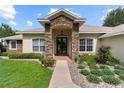 Close-up of a home's front entrance featuring a stone archway and landscaped garden at 12913 County Road 104B, Oxford, FL 34484