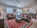 Open-concept living room with plush seating, a decorative rug, and a dining area, creating a warm and inviting space at 1406 Zest Ave, The Villages, FL 32163
