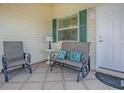 Covered porch showcasing comfortable seating with decorative pillows and a welcoming entrance at 1406 Zest Ave, The Villages, FL 32163