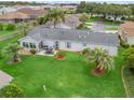 Aerial view showcasing a lush lawn, mature trees, and a patio with outdoor seating, set in a peaceful neighborhood at 17380 Se 111Th Ct, Summerfield, FL 34491