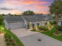 Charming single-story home with a two-car garage, brick driveway, and beautifully landscaped front yard during sunset at 17380 Se 111Th Ct, Summerfield, FL 34491