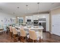 Bright, modern kitchen features an island with bar seating, stainless steel appliances, and wood floors at 1849 Sunshine Peak Dr, Minneola, FL 34715