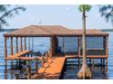 A waterfront covered boat dock with a boat lift and outdoor seating at 1956 Brantley Cir, Clermont, FL 34711