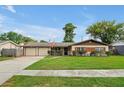 Charming ranch-style home with a well-manicured lawn, a two-car garage, and lush landscaping at 2007 Mosher Dr, Orlando, FL 32810