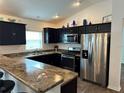 Modern kitchen featuring dark cabinets, stainless steel appliances, and a breakfast bar at 2441 Nellie Rd, The Villages, FL 32163