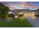 Charming single-story home with a well-manicured lawn, a decorative driveway, and a two-car garage at dusk at 2738 Morven Park Way, The Villages, FL 32162