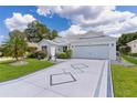 Charming single-story home featuring a decorative driveway, a two-car garage, and mature landscaping at 2738 Morven Park Way, The Villages, FL 32162