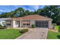 Charming home with a brick driveway and screened garage, complemented by a well-maintained front yard at 2766 Privada Dr, The Villages, FL 32162