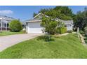 This home features a front lawn with driveway leading to the attached garage and mature landscaping at 2821 Mediterranean Loop, Tavares, FL 32778