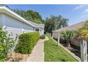 A walkway beside the home leads to a fenced yard area with greenery and tropical foliage at 2821 Mediterranean Loop, Tavares, FL 32778