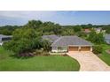 Aerial view showcasing the home's lush landscaping, large driveway, and three-car garage at 2904 Avalos Dr, The Villages, FL 32162
