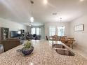 Open concept kitchen featuring granite countertops, stainless steel sink, and modern pendant lighting at 3181 Hill Point St, Minneola, FL 34715