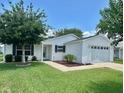 Home exterior featuring a well-maintained lawn and a one car garage at 3337 Candlebrook St, The Villages, FL 32162