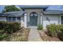 Inviting front entrance with a blue door, manicured bushes, and a cozy seating area at 33913 Sabal Way, Leesburg, FL 34748