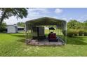 A tractor and trailer sit protected underneath a sturdy metal carport on a grassy lawn at 36535 Eagle Dr, Grand Island, FL 32735