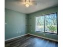 Bright bedroom features wood floors, a ceiling fan, and a large window with scenic views at 3930 Griffin Ave, Lady Lake, FL 32159