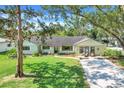 Single story home with beautiful green lawn, mature landscaping and cozy seating area on the front porch at 410 E Gulley Ave, Oakland, FL 34760