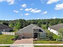 Beautiful aerial view of a single-story home with a paved driveway, lush backyard, and serene wooded backdrop at 440 Bellissimo Pl, Howey In The Hills, FL 34737