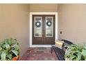 Inviting double front doors with decorative wreaths, a charming bench, and vibrant potted plants on a brick porch at 440 Bellissimo Pl, Howey In The Hills, FL 34737