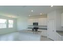 Open kitchen featuring white cabinets, granite counters, stainless appliances, and island with sink at 520 Silver Palm Dr, Haines City, FL 33844