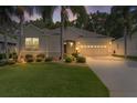 Charming single-story home at dusk with a well-manicured lawn and lush landscaping with palm trees at 541 Cokesbury Dr, The Villages, FL 32162