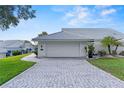 A lovely home featuring a pristine two-car garage, a brick driveway, and well-manicured landscaping at 6048 Topsail Rd, Lady Lake, FL 32159