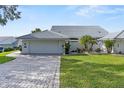 A lovely home featuring a pristine two-car garage, a brick driveway, and well-manicured landscaping at 6048 Topsail Rd, Lady Lake, FL 32159