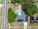 Aerial view of a property featuring a backyard pool, modern solar panels, and tree coverage at 6221 Ambassador Dr, Orlando, FL 32808