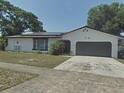 Charming single-story home featuring a two-car garage, well-maintained lawn, and mature trees at 6221 Ambassador Dr, Orlando, FL 32808