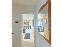 Hallway with view into kitchen, light walls, neutral tile flooring, mirror and artwork at 6221 Ambassador Dr, Orlando, FL 32808
