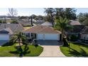 Well-maintained single-story home with three-car garage, lush landscaping, and mature palm trees at 9430 Se 176Th Saffold St, The Villages, FL 32162