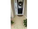 Welcoming front porch with a decorated door and a neutral-toned mat, framed by greenery at 9430 Se 176Th Saffold St, The Villages, FL 32162
