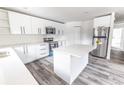 Modern kitchen boasts sleek white cabinetry, a large island with quartz countertops, and stainless steel appliances at Lot 21 Indian Estates Cr 423, Lake Panasoffkee, FL 33538