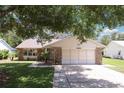 Charming single-story home with stone accents, lush lawn, and mature shade trees at 1011 Dundee Cir, Leesburg, FL 34788