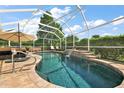 A relaxing screened-in pool with a waterfall feature and patio seating, surrounded by lush landscaping at 1175 Johnston Path, The Villages, FL 32162
