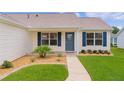 Welcoming front entry featuring a blue door, decorative shutters, manicured landscaping, and a concrete walkway at 1313 Arredondo Dr, The Villages, FL 32162