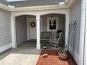 Inviting covered porch with seating, a floral wreath, and a decorative wind chime at 1512 Nueva Pl, The Villages, FL 32159