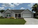 Lovely single-story home featuring a well-manicured lawn, flower beds, and a two-car garage at 1512 Nueva Pl, The Villages, FL 32159