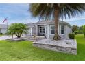 The backyard of the home features lush green grass, palm trees, and a back patio seating area at 2082 Vision Ct, The Villages, FL 32163
