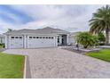 Charming home featuring a three-car garage, well-maintained lawn, and tropical landscaping at 2082 Vision Ct, The Villages, FL 32163
