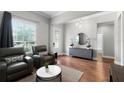 Bright living room with wood floors, a modern light fixture and matching gray chairs at 313 Blue Cypress Dr, Groveland, FL 34736
