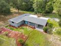 Aerial view of a well-maintained home featuring a landscaped yard with colorful plants and a cozy carport at 4123 County Road 124, Wildwood, FL 34785