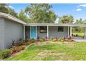 Charming home featuring a blue door, a cozy carport and a landscaped front yard with colorful plants at 4123 County Road 124, Wildwood, FL 34785