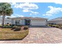 Inviting single-story home with a brick driveway, two-car garage, and well-maintained landscaping at 4987 Belted Kingfisher Dr, Oxford, FL 34484