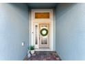 Close-up of the front door with decorative wreath and sidelights, creating a warm and inviting entrance at 4987 Belted Kingfisher Dr, Oxford, FL 34484