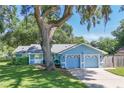Quaint one-story home with a mature tree, two-car garage, and a freshly mowed lawn at 5380 County Road 122, Wildwood, FL 34785