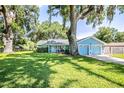 Inviting home exterior showcasing lush lawn, mature trees, and a two-car garage at 5380 County Road 122, Wildwood, FL 34785