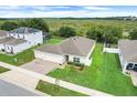 Aerial view of a well-manicured lawn and single story home with a three-car garage, surrounded by green space at 641 Black Eagle Dr, Groveland, FL 34736