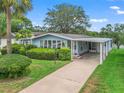 Well-maintained home with carport, manicured lawn, and lush landscaping at 727 Turnberry Ln, The Villages, FL 32159